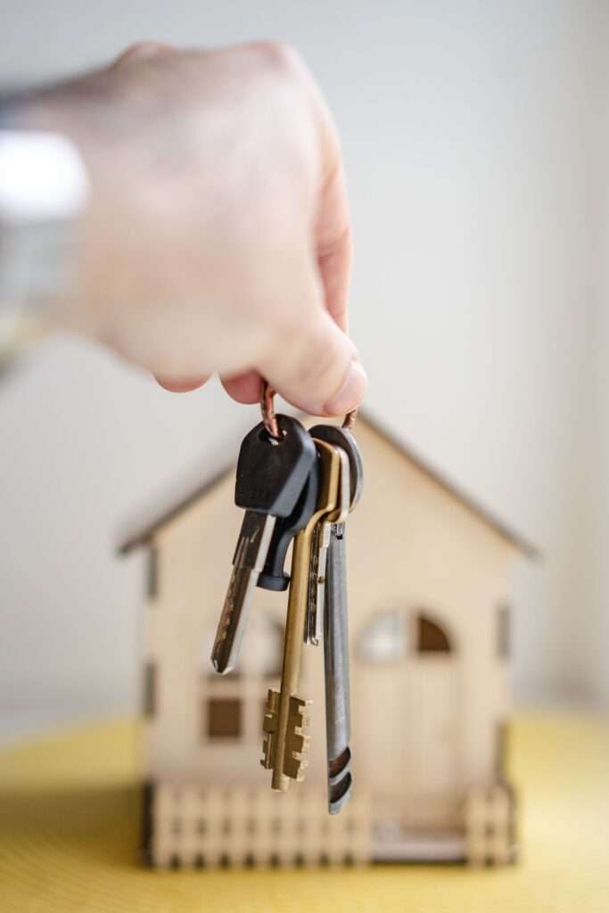 A picture of a man holding a key in front of a house. Tenant screening