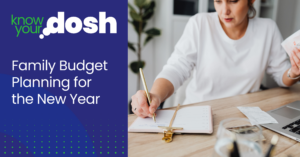 woman at desk with pen and paper in hand working on family budget