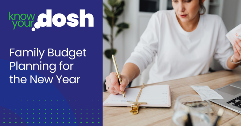woman at desk with pen and paper in hand working on family budget