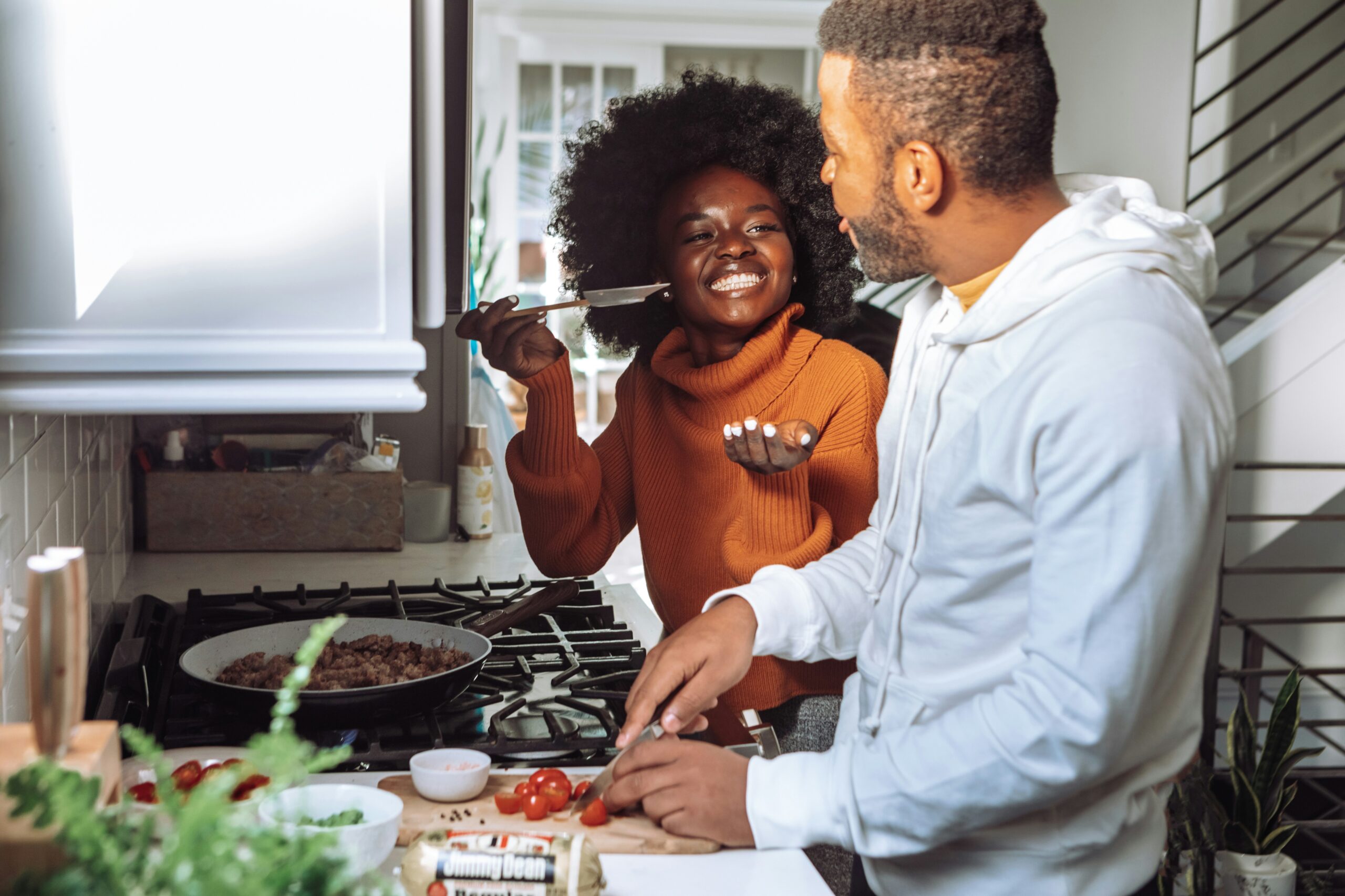 couple in kitchen making a meal and smiling