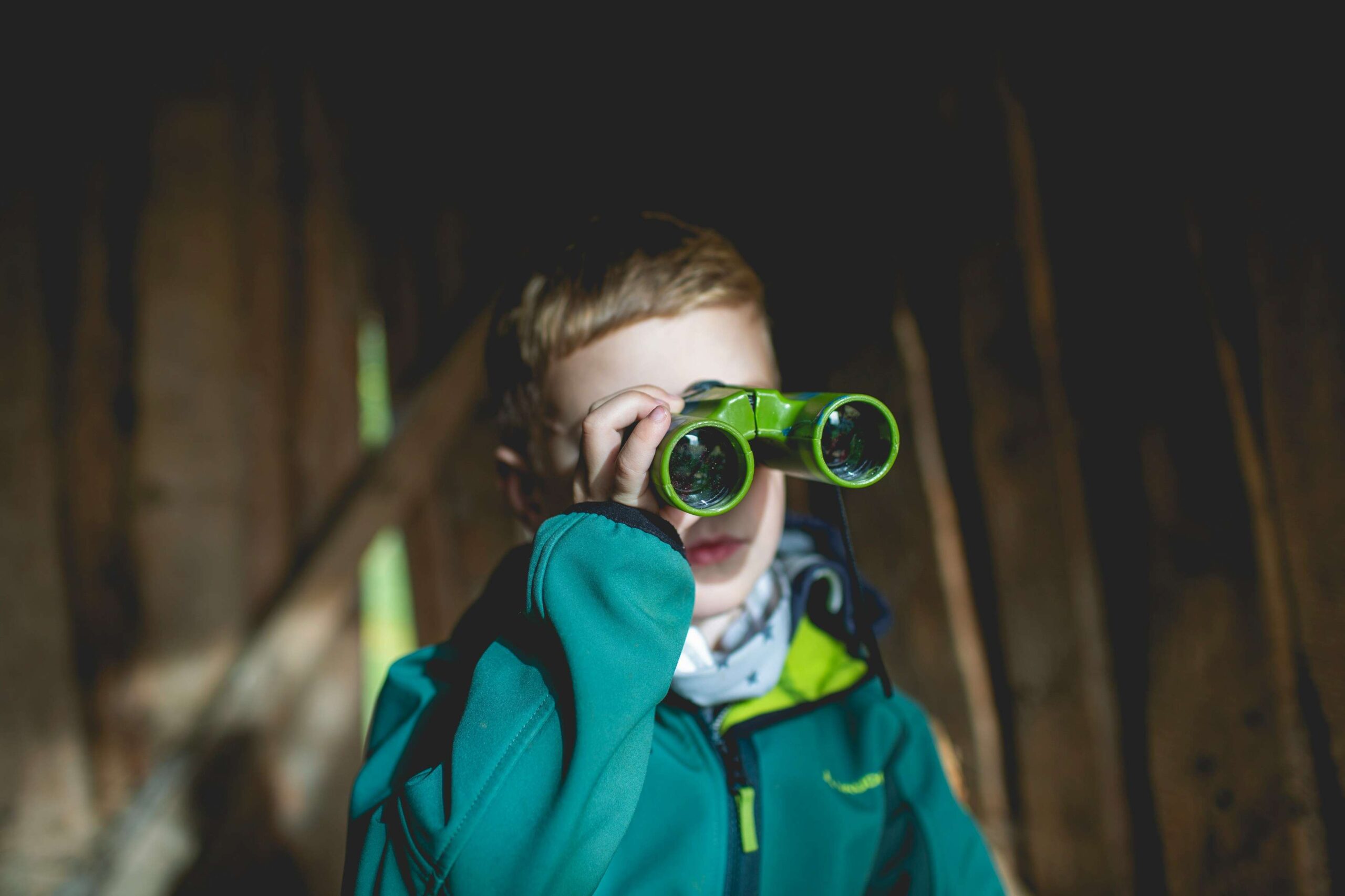 kid looking through green binoculars